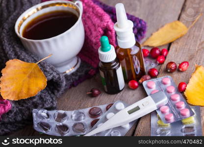 Fall and health care. home pharmacy - cup of tea, pills and thermometer on a wooden background