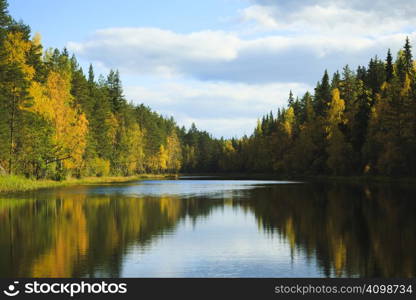 Fall colored forest reflections on the blue water