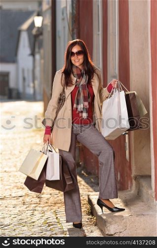 Fall elegant woman carrying shopping bags walking city street sunset