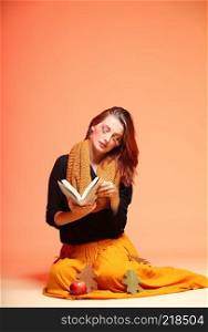 Fall. Fashion woman in autumn color student girl in full length with book long false orange eye-lashes