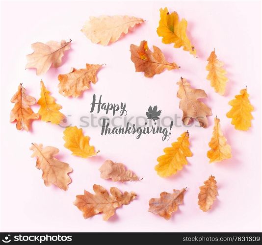 Fall leaves frame on pink flat lay autumn background with happy thanksgiving greetings. Fall leaves autumn background