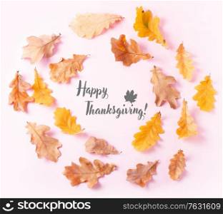 Fall leaves frame on pink flat lay autumn background with happy thanksgiving greetings. Fall leaves autumn background