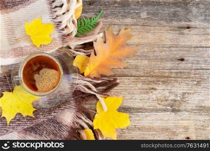 Fall leaves with cup of coffee on woolen plaid autumn background with copy space. Fall leaves autumn background