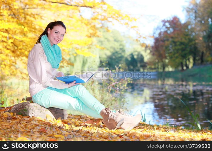 Fall lifestyle concept. Casual young woman girl relaxing in autumnal park reading book. Golden colorful leaves background