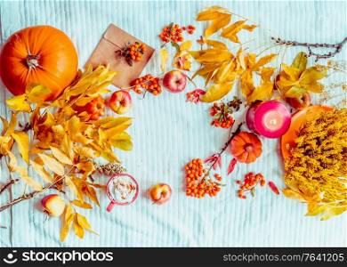 Fall mood with various autumn decoration: Pumpkin, cup of hot chocolate, candle on blue knitted blanket. Frame. Flat lay. Top view