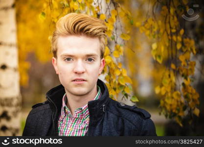 Fall season and people concept. Portrait of young stylish fashionable man in plaid shirt and jacket against autumn birch trees. Yellow leaves background