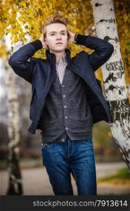 Fall season and people concept. Portrait of young stylish fashionable man in plaid shirt and jacket against autumn birch trees. Yellow leaves background