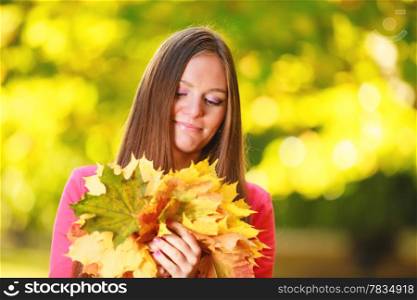 Fall season. Portrait of happy girl young woman with bunch of colorful leaves in autumnal park forest. Outdoor.