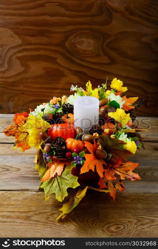 Fall table centerpiece with candle and silk maple leaves, vertical. Thanksgiving greeting with fall decor. Fall centerpiece. Thanksgiving background. . Fall table centerpiece with candle and silk maple leaves, vertic