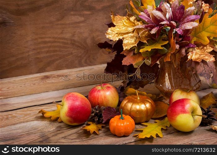 Fall table centerpiece with leaves, purple flowers, golden pumpkin and apples, copy space