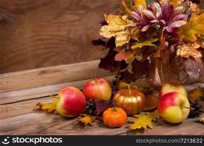 Fall table centerpiece with leaves, purple flowers, golden pumpkin and apples, copy space