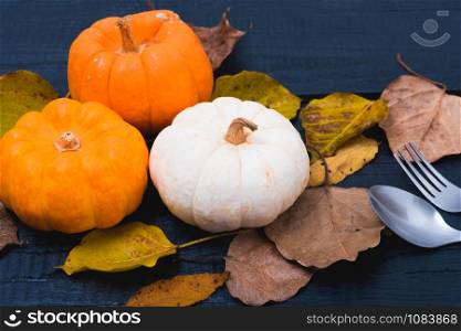 Fall Thanksgiving and Halloween pumpkins, dry leaves on wooden background