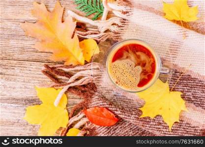 Fall yellow leaves with cup of coffee on woolen plaid autumn background, retro toned. Fall leaves autumn background