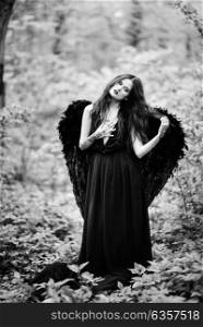 Fallen angel with black wings in the old forest