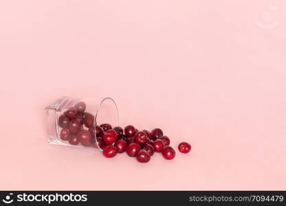 Fallen glass with scattered red ripe sweet cherry on pink background. Concept of fresh natural juice, smoothies, healthy eating or diet. Template for text or your design. Copy space.. Fallen glass with scattered red ripe sweet cherry on pink background. Concept of fresh natural juice, smoothies, healthy eating or diet. Template for text or your design. Copy space