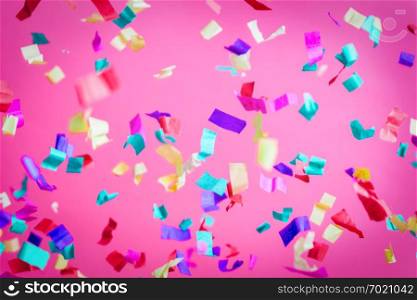 Falling confetti on pink background. Party, birthday celebration. Colorful festive background.. Falling confetti on pink background.