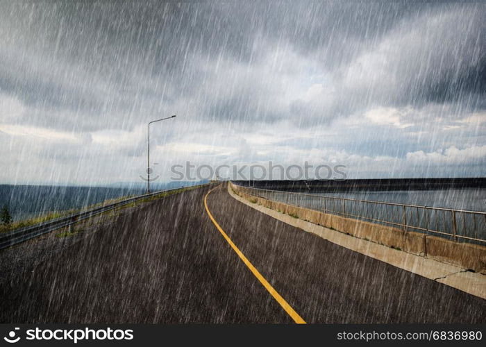 falling rain in road on the ridge of Lam Takong reservoir dam, Nakhon Ratchasima, Thailand