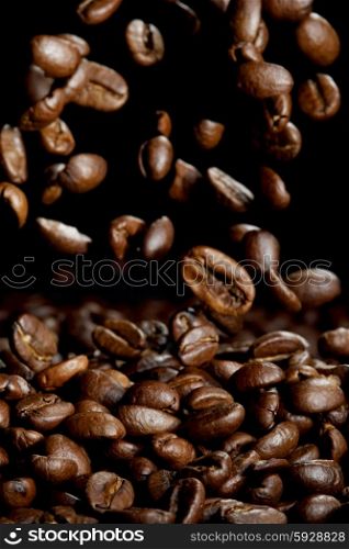 Falling roasted coffee beans on black background
