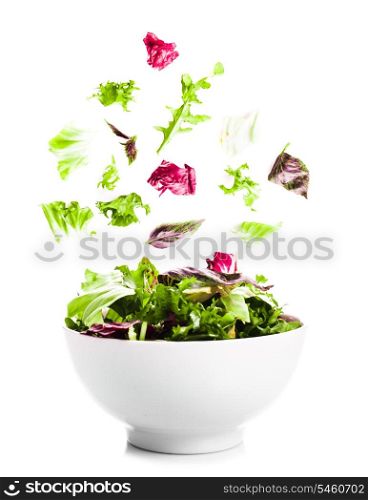 Falling salad with green leaves in a bowl on the white