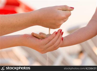 Falling sand from a hand of the woman in a hand of the child