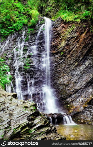 Falls among the black rocks in the green forest. Falls among the black rocks