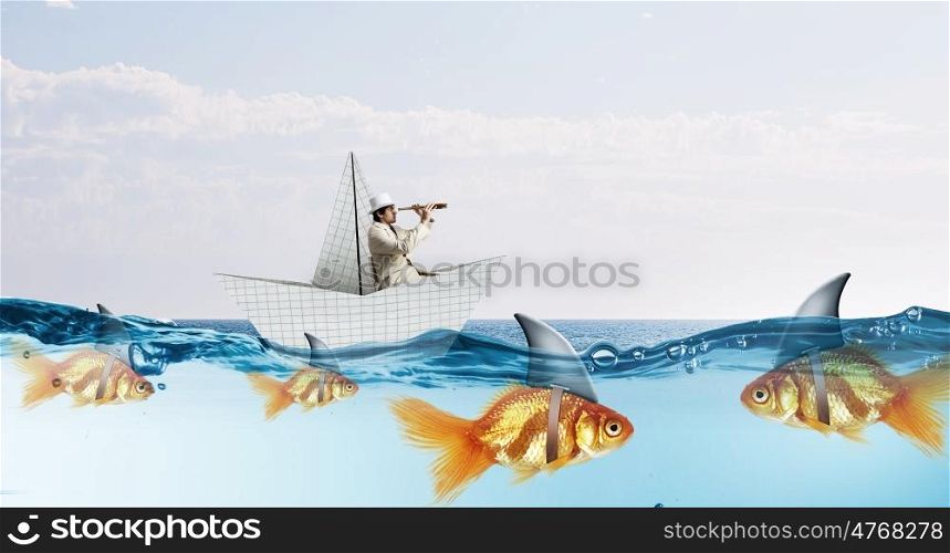 False risk for your business. Concept of fake threat when businessman float in paper ship and sharks in water appear to be goldfish