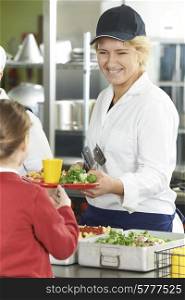 Famale Pupil In School Cafeteria Being Served Lunch By Dinner Lady