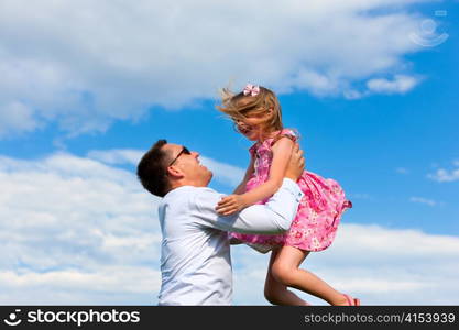 Family affairs - father and daughter playing in summer; he is throwing her into the air