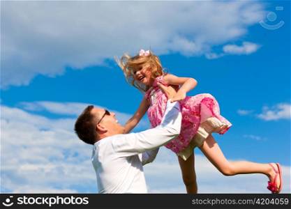 Family affairs - father and daughter playing in summer; he is throwing her into the air