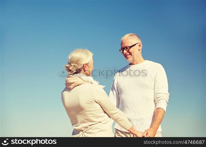 family, age and people concept - happy senior couple holding hands talking outdoors