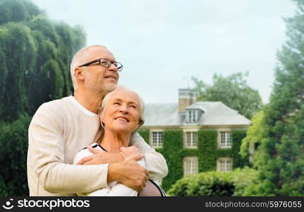 family, age, home, real estate and people concept - happy senior couple hugging over living house background