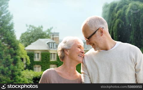 family, age, home, real estate and people concept - happy senior couple hugging over living house background