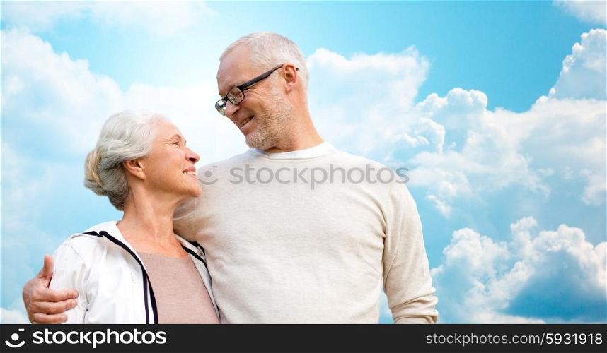 family, age, love, relations and people concept - happy senior couple over blue sky and clouds background