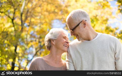 family, age, season and people concept - happy senior couple over autumn trees background
