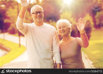 family, age, tourism, gesture and people concept - senior couple waving hands in city park. senior couple hugging in city park. senior couple hugging in city park