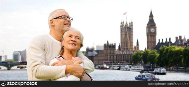 family, age, tourism, travel and people concept - happy senior couple over houses of parliament or palace of westminster and big ben clock tower in london