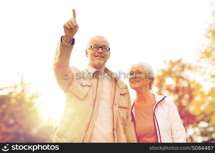 family, age, tourism, travel and people concept - senior couple pointing finger in park. senior couple in park. senior couple in park