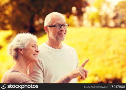 family, age, tourism, travel and people concept - senior couple pointing finger in park