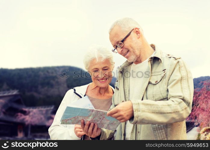 family, age, tourism, travel and people concept - senior couple with map and over asian village and mountains landscape background