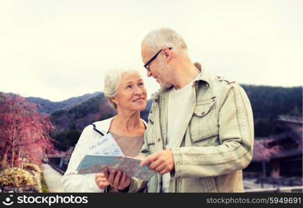 family, age, tourism, travel and people concept - senior couple with map and over asian village and mountains landscape background