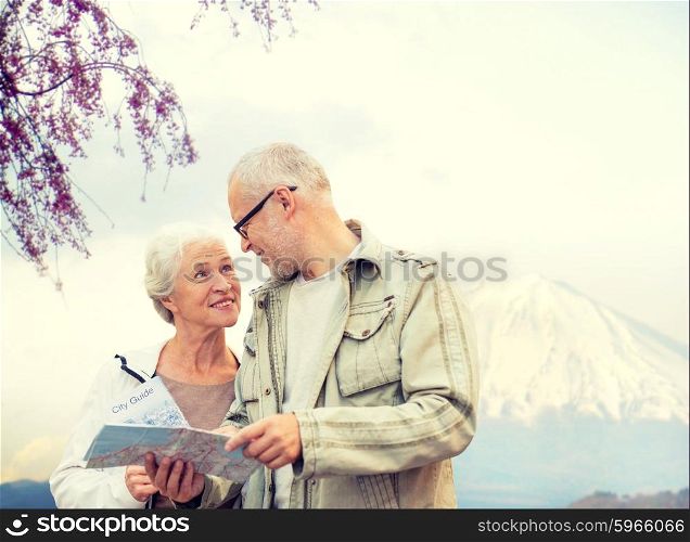 family, age, tourism, travel and people concept - senior couple with map and city guide talking over japan mountains background