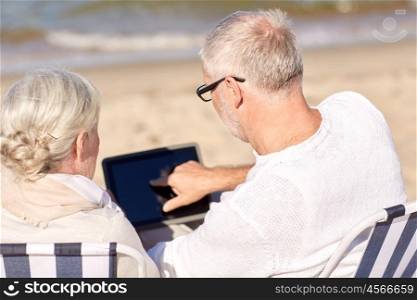 family, age, travel, technology and people concept - close up of senior couple with tablet pc computer sitting on deck chairs on summer beach