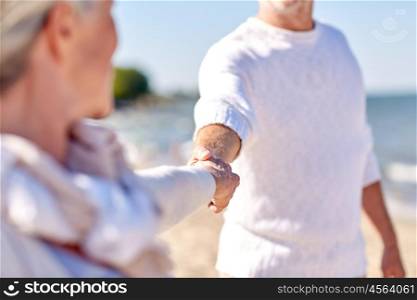 family, age, travel, tourism and people concept - close up of happy senior couple holding hands on summer beach