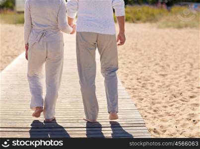 family, age, travel, tourism and people concept - close up of happy senior couple holding hands and walking on summer beach