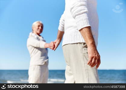 family, age, travel, tourism and people concept - close up of happy senior couple holding hands on summer beach