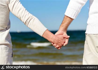 family, age, travel, tourism and people concept - close up of senior couple holding hands on summer beach