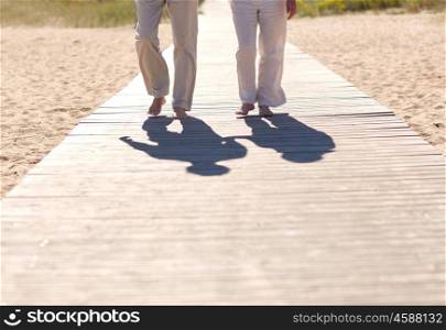 family, age, travel, tourism and people concept - close up of senior couple walking on summer beach