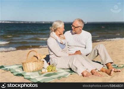 family, age, travel, tourism and people concept - happy senior couple having picnic and talking on summer beach
