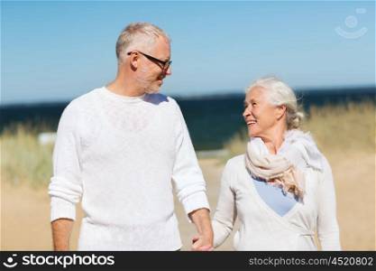 family, age, travel, tourism and people concept - happy senior couple holding hands and walking on summer beach