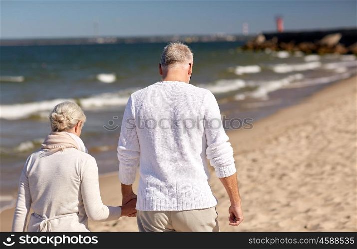 family, age, travel, tourism and people concept - happy senior couple holding hands and walking along summer beach